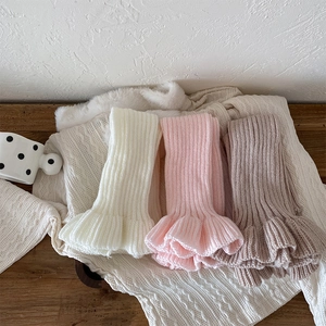 Detail of knitted leg warmers with ruffle trim in cream, pink and coffee colors