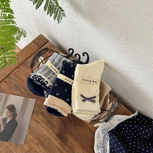 Three pairs of floral and bow mid-calf socks displayed in a metal basket on wood