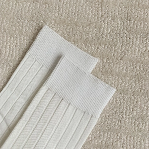 Detailed close-up of white ribbed knit fabric showing the fine texture of cotton socks