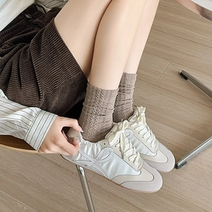 Gros plan de baskets rétro en daim beige portées avec un pantalon en velours côtelé