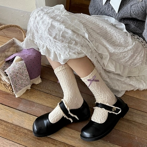 Detail of socks with purple bow and lace ruffles paired with black Mary Jane shoes