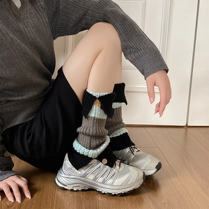 Detailed view of striped knit leg warmers with vintage buttons and mixed color blocks