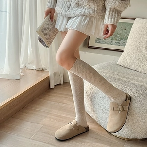 Detail of khaki suede mule clogs with metal buckle and vertical striped knit long socks