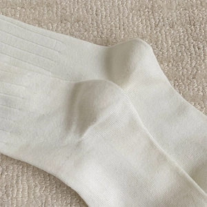 Detail of white ribbed cotton socks featuring reinforced heel and high-elasticity texture