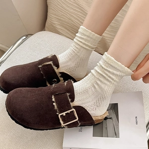 Gros plan de sabots en daim marron avec boucle en métal et doublure polaire blanche