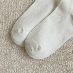 Detailed close-up of white knitted cotton socks showing vertical ribbed texture and toe seam