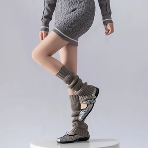 Close-up of dark grey cable knit leg warmers paired with silver Mary Jane shoes