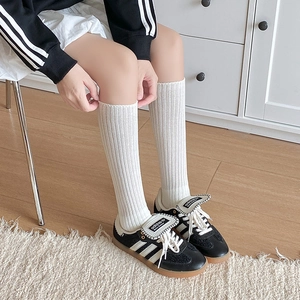Detail of white ribbed knit knee-high socks showing texture and elastic cuff comfort
