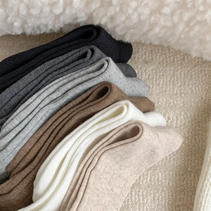 Close-up of stacked vertical ribbed knit socks in neutral tones on white fleece