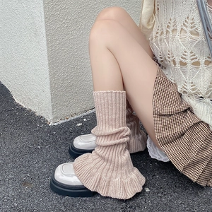 Detail of cable-knit ballet style leg warmers in beige, styled with platform leather shoes