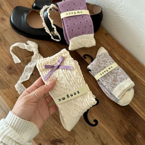 Detailed view of floral socks with purple bows and lace trim in vintage packaging