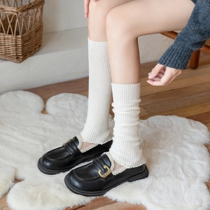 Women's cream white vertical rib knit leg warmers paired with black fur-lined loafers