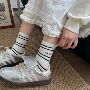 Close-up of white striped cotton socks with HAPPY embroidery and colorful dots texture
