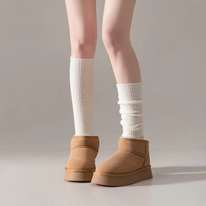 Detail of cream ribbed wool leg warmers paired with brown suede winter snow boots