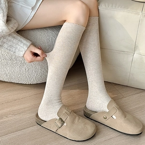 Beige ribbed calf socks with vertical stripes paired with matte clog slippers for autumn