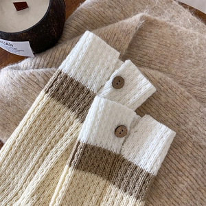 Detail of striped knit leg warmers featuring contrast colors and vintage wooden buttons