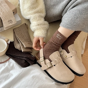 Detail of wool knit socks with letter embroidery and cozy vintage suede mules in winter home setting