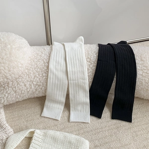 Close-up of ribbed knit texture on black and white high socks over soft wool background