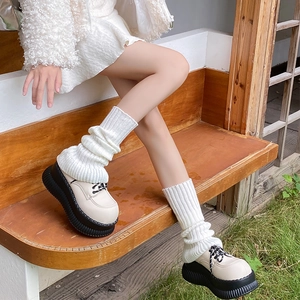 Detail shot of white ribbed knit leg warmers paired with chunky platform loafers