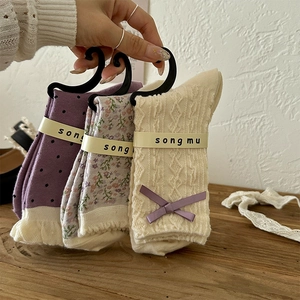Detailed view of women's purple floral socks with lace edges and elegant silk bows