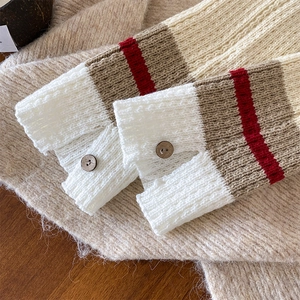 Close-up of knit leg warmer detail with striped pattern and wooden button closure
