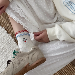 Detail of white cotton socks with wavy red blue trim and cute bear heart embroidery
