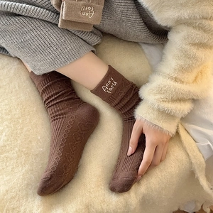 Close-up of thick coffee brown wool socks with custom white letter embroidery