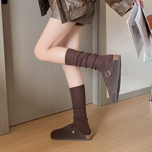 Detailed view of dark brown suede clogs with metal buckle and thick knit socks