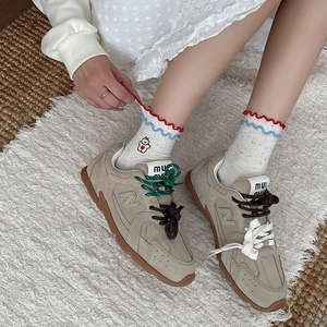 Retro khaki suede sneakers with multi-color laces on a cozy plush rug background