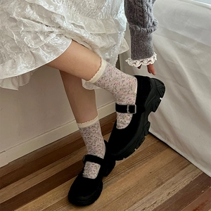 Detail of black Mary Jane shoes with thick soles paired with floral patterned crew socks