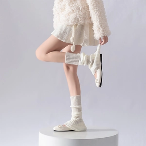 Close-up of white knit leg warmers with vertical ribbed texture and lace edge detail
