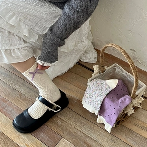 Close-up of vintage cotton socks with purple bow and floral patterns in a woven basket