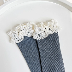Detailed close-up of dark grey cotton socks with elegant white lace trim on a white tray