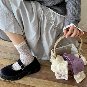 Close-up of floral socks with lace cuffs and bows paired with Mary Jane shoes