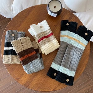 Close-up of striped knit leg warmers featuring decorative vintage wood buttons