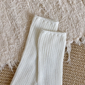 Close-up of white ribbed knit long socks texture on a natural rustic background