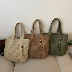 Woven straw tote bags with tassel details in neutral tones on a cozy sofa
