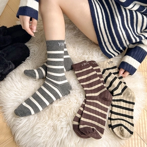 Close-up of striped wool socks with embroidered letters on cozy white carpet