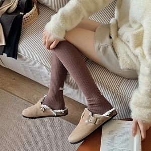 Detail of coffee brown ribbed wool socks with cloth label paired with suede clogs