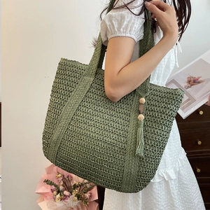 Green straw tote bag with tassels and wooden beads for casual beach outings