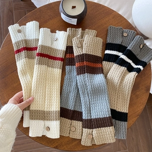 Detail of colorful striped knitted leg warmers with vintage wooden button accents