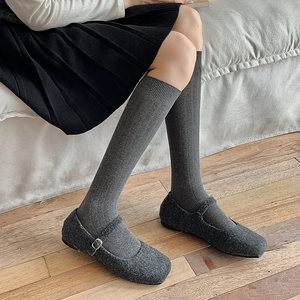 Grey vertical striped knee-high knit socks paired with grey Mary Jane shoes in retro style
