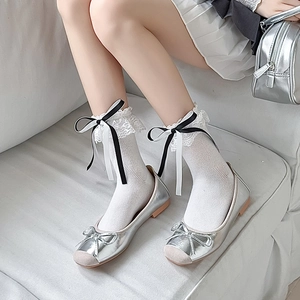 Detailaufnahme weißer Spitzensocken mit Schleifen und silbernen Ballerina-Schuhen