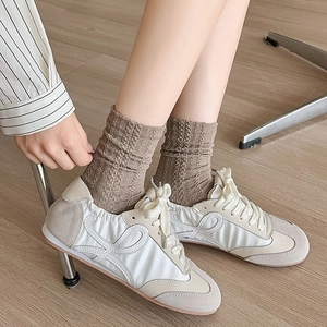 Chaussettes mi-hautes vintage à côtes marron avec baskets en cuir sur sol en bois