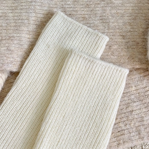 Close-up of cream white ribbed knit wool leg warmers showing soft textured material