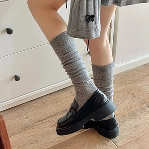 Detail of grey wool knee-high socks with fashion tag and black platform loafers