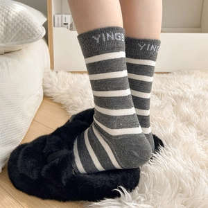 Close-up of gray and white striped wool socks with embroidered letter detailing