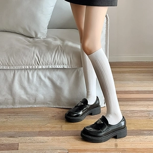 Detail shot of black leather platform loafers with ribbed white socks in college style
