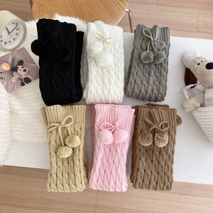 Detail of cable knit leg warmers in six colors with pom-pom ties and cozy winter texture