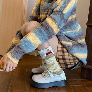 Detailed view of cream knitted leg warmers with red and brown stripe accents for women